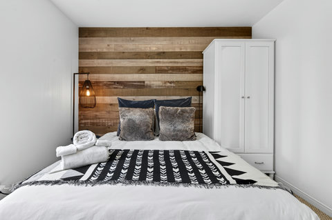 Cozy bedroom with wood accent wall, soft lighting, and crisp modern style