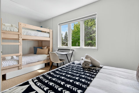 Bright family-friendly bedroom with bunks, workspace, and leafy views