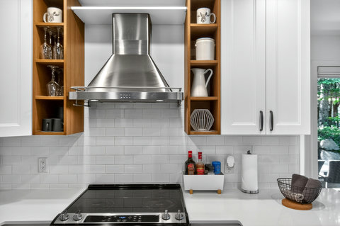 Modern white kitchen with sleek range hood and warm open shelving