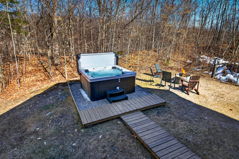 Secluded backyard oasis with hot tub, fire pit & forest views.