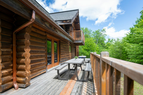 Sunny log-cabin deck with picnic table and forest views—perfect escape