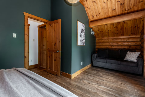 Cozy log cabin bedroom with vaulted wood ceilings and lounge sofa