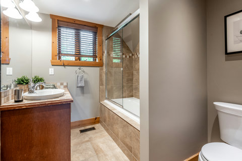 Bright bathroom with tiled tub-shower and warm rustic wood accents