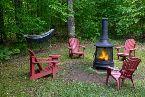 Cozy woodland fire pit with Adirondack chairs and a relaxing hammock