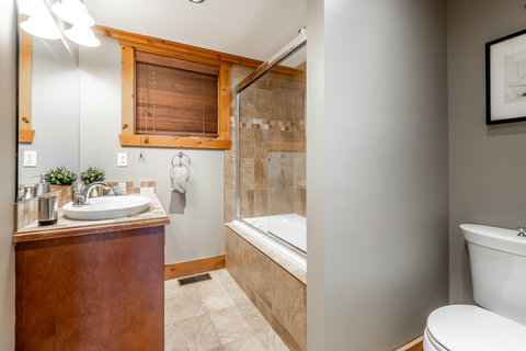 Warm rustic bathroom with tiled tub-shower and spacious vanity