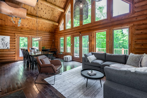 Bright log cabin great room with soaring ceilings and stunning forest views