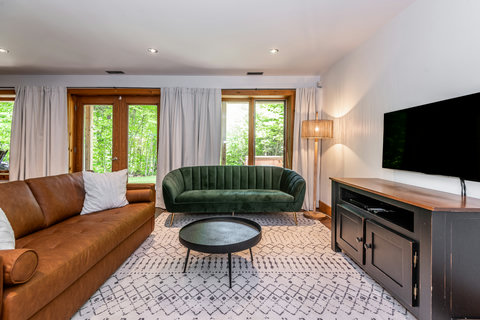Bright modern lounge with forest views, cozy seating, and large TV