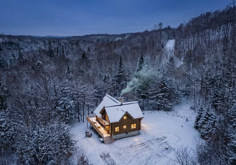 Secluded snowy cabin retreat with glowing lights and forest views