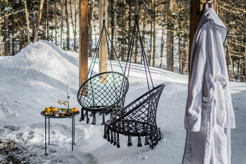 Cozy winter retreat with hanging chairs, snowy views, and spa-style touches