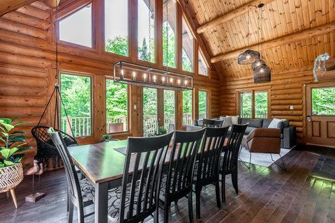 Soaring log cabin great room with forest views and a large dining area