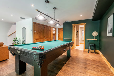 Stylish game room with pool table, warm wood accents, and lounge space