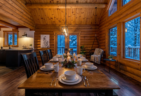 Cozy log cabin dining with snowy forest views and rustic charm