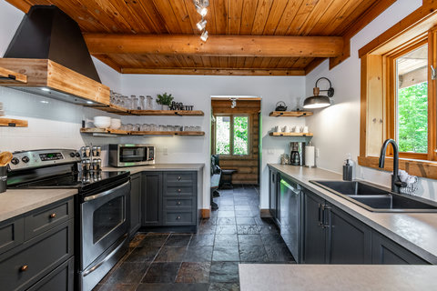 Rustic-modern kitchen with open shelving, natural light, and sleek finishes