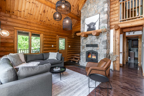 Cozy log cabin great room with stone fireplace and soaring wood ceilings