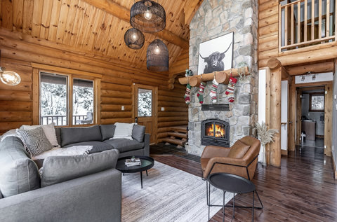 Cozy log cabin great room with stone fireplace and soaring wood ceilings