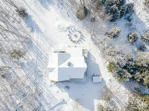 Snow-covered woodland retreat with private yard and outdoor gathering space