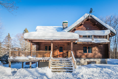 Cozy snow-covered log cabin with porch and peaceful winter views