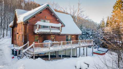 Cozy log cabin with wraparound deck, balcony & snowy hot tub retreat