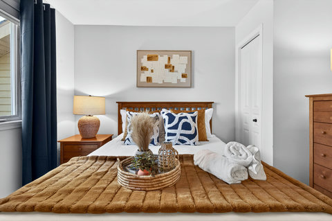 Cozy bedroom with warm wood, plush throw, and fresh rolled towels