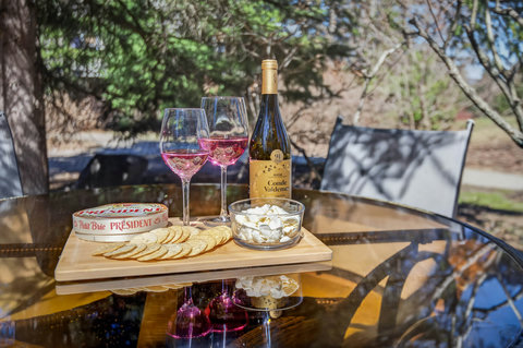 Sunlit patio with wine-and-cheese setup—relaxing alfresco retreat.