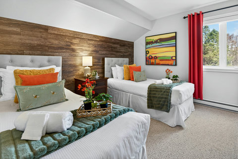 Bright twin room with wood accent wall, treetop view, and plush linens