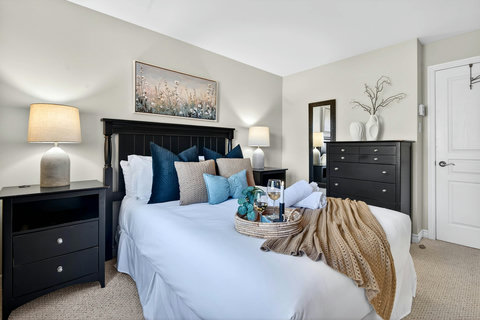 Serene bedroom with plush bedding, soft lighting, and chic black accents.