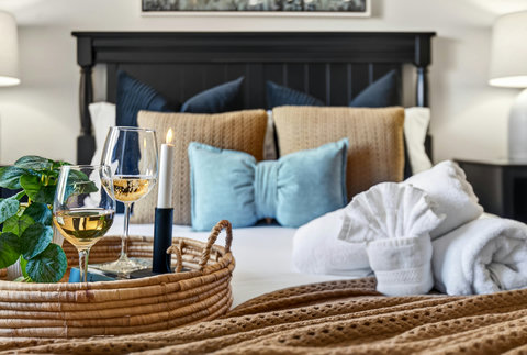 Cozy retreat with plush bedding, wine-and-candle tray, and spa towels