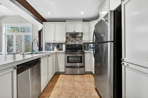 Bright U-shaped kitchen with stainless appliances & ample prep space