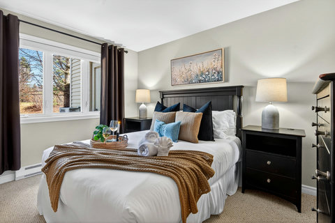 Sunlit, stylish bedroom with plush bedding and garden-view window.
