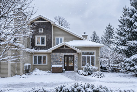 Charming snowy chalet with stone entry and serene winter surroundings