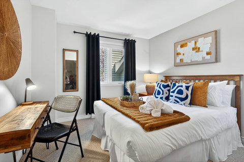Bright, cozy bedroom with plush bed, desk workspace, and stylish accents.