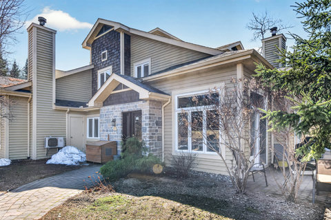 Cozy chalet-style townhome with stone entry, big windows, and patio