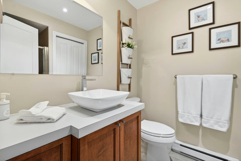 Bright, modern bath with vessel sink, warm wood, and fresh towels