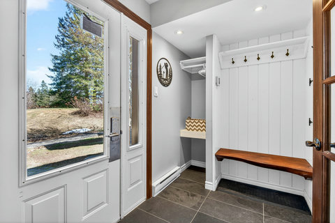 Bright mudroom with slate floors, gear hooks, and live-edge bench