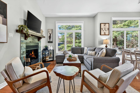 Bright lounge with fireplace, forest views, and comfy sectional seating