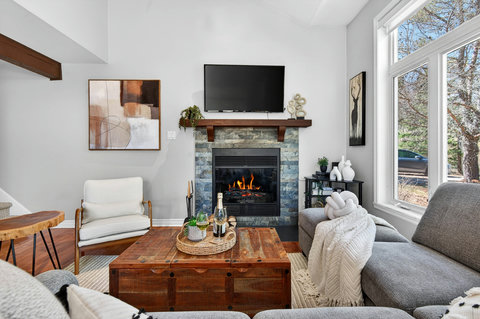 Cozy living room with stone fireplace, smart TV & sunlit windows