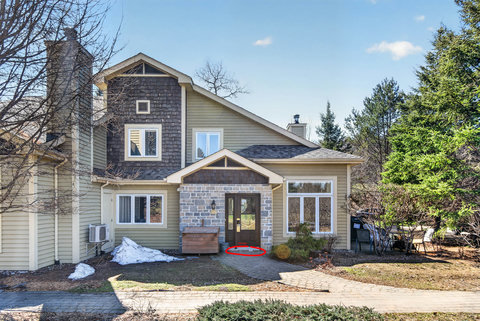 Charming stone-front retreat with paver walkway, large windows, wooded setting