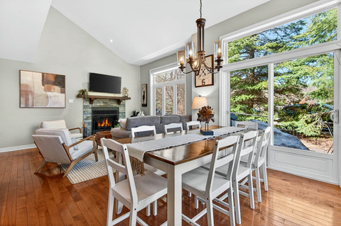 Sunlit great room with fireplace and dining for 8 by forest views