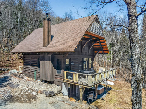 Woodland log cabin with deck dining, grill, and private hot tub retreat.