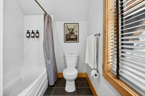 Bright bathroom with subway-tile tub, window light, and stocked toiletries.