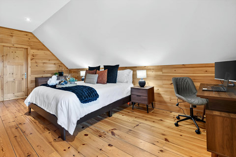 Cozy loft suite with warm wood, queen bed, and dedicated work desk.
