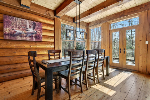 Rustic, sunlit dining—seats six with forest views and French doors to deck.