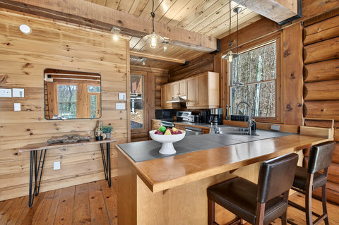 Warm log cabin kitchen with island, forest views, and modern amenities