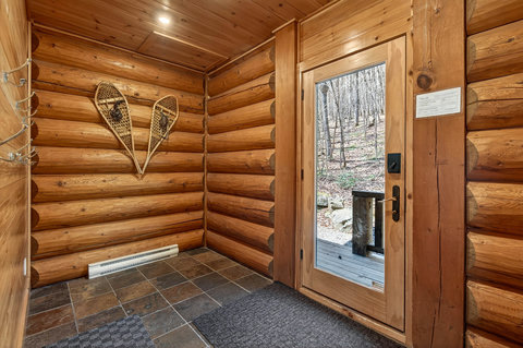 Welcoming log-cabin mudroom with slate tile and forest-view door