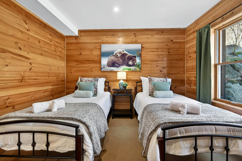 Cozy twin-bed cabin room with wood walls and nature-view window