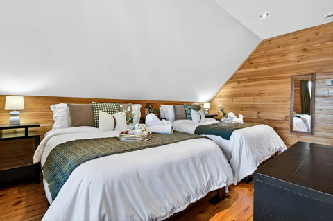 Cozy loft bedroom with two plush beds, rustic wood walls, and soft lighting