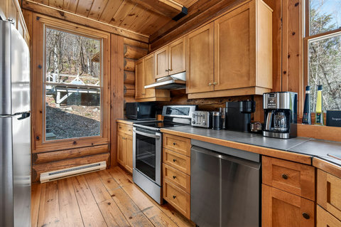 Cozy log-cabin kitchen with stainless appliances and a coffee bar view.