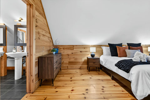 Warm wood-lined bedroom with ensuite, plush bedding, and modern style