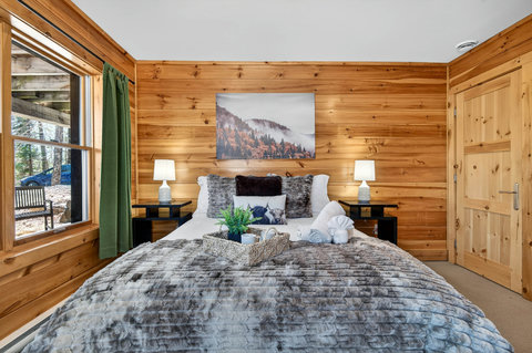 Cozy cabin bedroom w/ plush bedding, forest views & warm wood accents