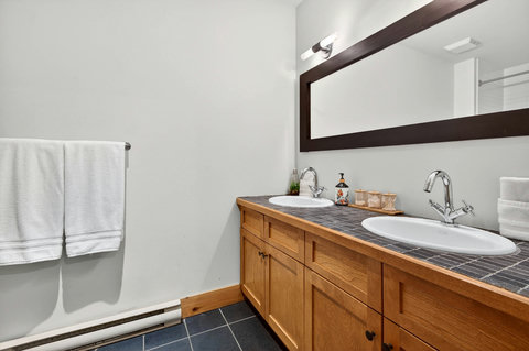 Modern bath with double vanity, slate floors, and large mirror